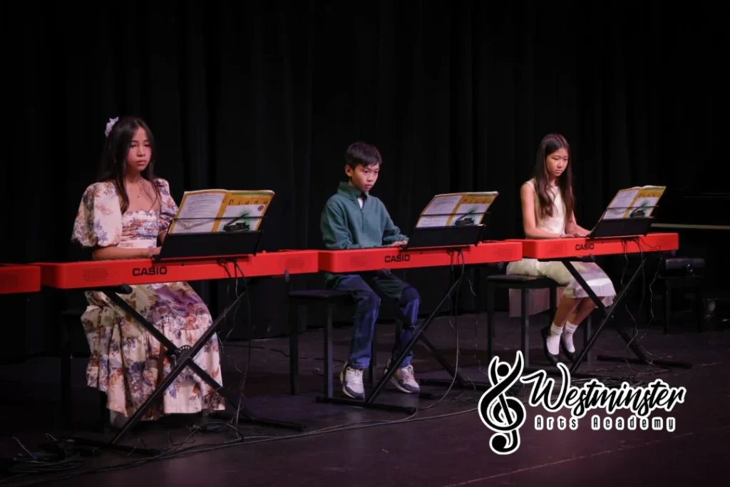 Students seated at keyboards playing together in a group piano class at Westminster Arts Academy.